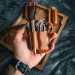 Leather EDC Pocket Organizer holding knife, flashlight, pen, and prybar in hand, full-grain vegetable-tanned leather design.